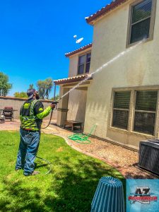 The gentle soft washing process in action on a residential stucco home. The image shows built-up dirt and grime running down the wall, revealing the pristine clean surface underneath.